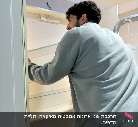 אדם מתקין מדף זכוכית בחדר אמבטיה